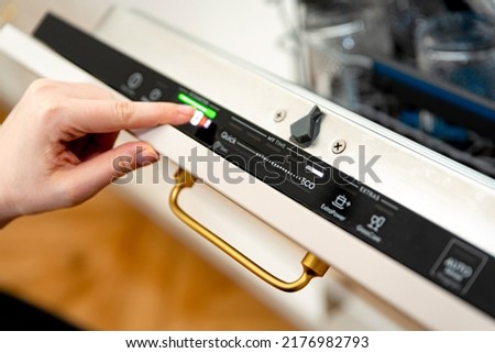 Woman choosing eco mode program on the digital control panel of the dishwasher. Eco cycle of dishwashing machine, energy saving at home concept Royalty-Free Stock Photo #2176982793