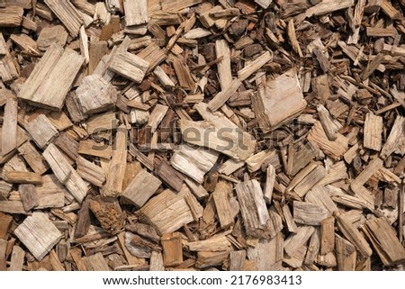 Wooden splinters closeup. Decorative wood chips texture. Natural material pattern of yellow wooden pieces of tree bark. Full filled frame picture. View from above. Sunny day with shadows.