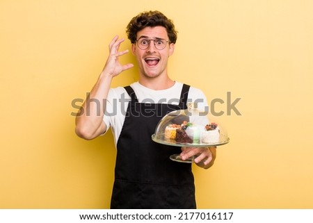 young handsome guy screaming with hands up in the air. home made cakes concept