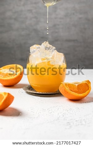 Bumble cold refreshing coffee drink with freshly squeezed orange juice, espresso and ice in the making. Pouring orange juice into the glass. Royalty-Free Stock Photo #2177017427