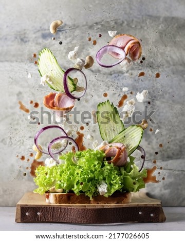 Sandwich with flying ingredients on wooden board on textured background. Levitation healthy food creative concept. Vertical orientation Royalty-Free Stock Photo #2177026605