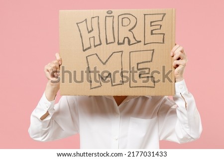 Young employee business secretary woman corporate lawyer wearing classic formal white shirt work in office hiding cover face with cardboard sign card need job isolated on pastel pink background studio