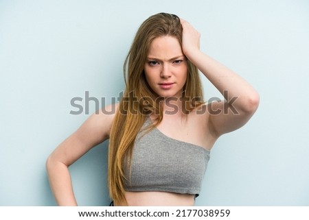 Young caucasian woman isolated on blue background tired and very sleepy keeping hand on head.