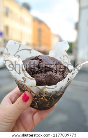 Hand holding muffin from a bakery in the Oslo city.