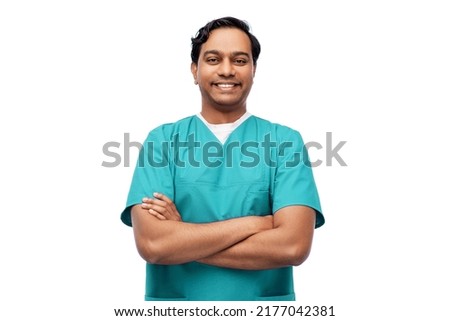 healthcare, profession and medicine concept - happy smiling indian doctor or male nurse in blue uniform with crossed arms over white background Royalty-Free Stock Photo #2177042381