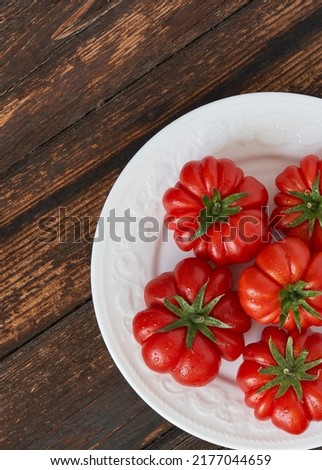 Fresh red tomatoes raf, on white plate on wooden background. Food concept. Copy space. Top view