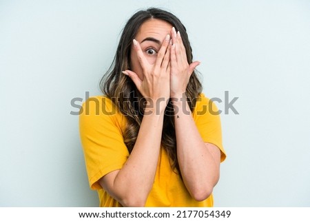 Young caucasian woman isolated on blue background blink through fingers frightened and nervous. Royalty-Free Stock Photo #2177054349