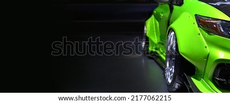 Front headlights of green modify car on black background, copy space