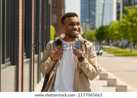 A black man talking on a mobile phone into a loudspeaker walking down the street