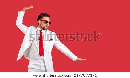 Overjoyed young man in suit isolated on red studio background feel overjoyed dancing. Happy male in formalwear have fun make dancer moves. Fun and entertainment concept.