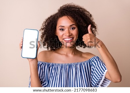 Photo of attractive charming person show thumb up empty space telephone display isolated on beige color background
