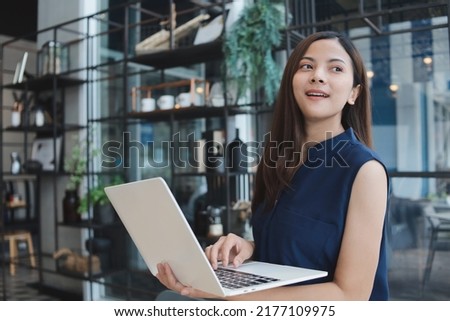 Beautiful Asian woman in casual blue shirt using laptop at cafe, Happy Freelancer woman working with laptop.