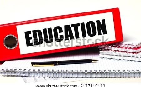 On the desktop are notebooks, a pen and a red folder for papers with the text EDUCATION. Business concept