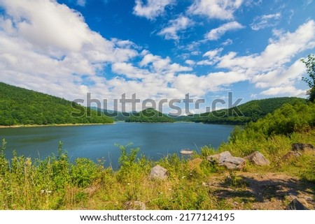 Magnificent sunny summer scenery with symmetric mountain on lake island and mountains on background. Location place: Zetea Lake on the Tarnava Mare River, Eastern Carpathians, Romania. Royalty-Free Stock Photo #2177124195