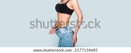 Dieting. Woman showing slim body after sport trainings, healthy eating. Weight loss concept. Thin woman in big pants, weight loss concepts. Slim girl wearing oversized pants. Woman shows weight loss. Royalty-Free Stock Photo #2177134685