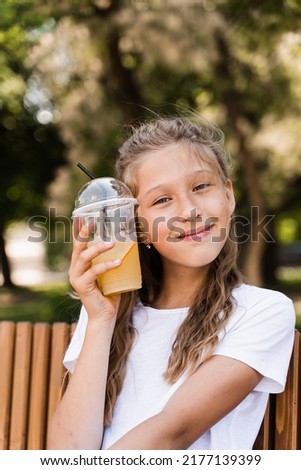 Summer lemonade cocktail outdoor. Happy girl holding cup with orange lemonade and smiling and laughing