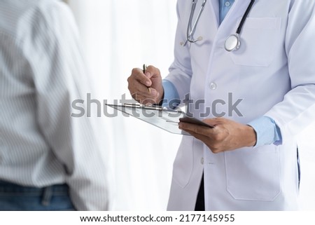 Doctor and patient sitting and talking at medical examination at hospital office, close-up. Therapist filling up medication history records. Medicine and healthcare concept. Royalty-Free Stock Photo #2177145955