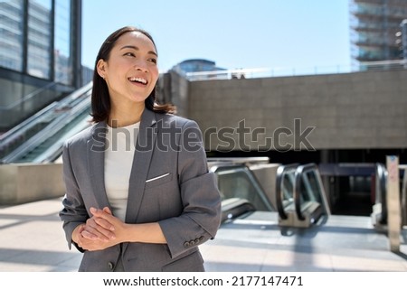 Young happy smiling beautiful Asian business woman, successful entrepreneur wearing suit standing in subway looking at ads copy space urban big city location outdoors. Royalty-Free Stock Photo #2177147471
