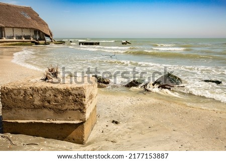 Old fishery and old concrete structure remains from its annexes on the wild Perisor beach (between Danube Delta and Black Sea) slowly collapsing under the eroding sea waves in early spring Royalty-Free Stock Photo #2177153887