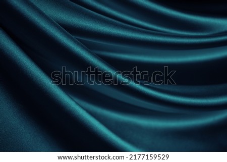  Blue green silk satin. Soft wavy folds. Shiny silky fabric. Dark teal color elegant background with space for design. Curtain. Drapery. Christmas, valentine, anniversary, celebration concept.         Royalty-Free Stock Photo #2177159529