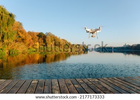 Drone copter with digital camera, blur river on background Royalty-Free Stock Photo #2177173333