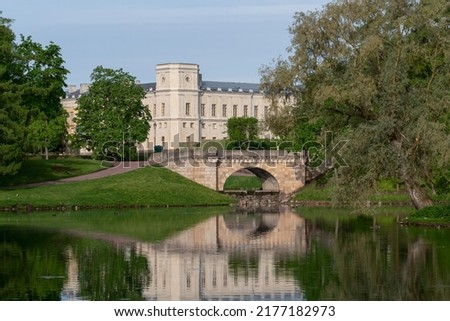 View of the Karpin Bridge over the cascade between the Karpin Pond and the White Lake of Gatchina Park and the Gatchina Palace in the background on a sunny summer day, Gatchina, St. Petersburg Russia Royalty-Free Stock Photo #2177182973