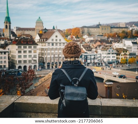 Young beautiful pretty blonde tourist girl in warm hat and coat with backpack walking at cold autumn in Europe city enjoying her travel in Zurich Switzerland Royalty-Free Stock Photo #2177206065