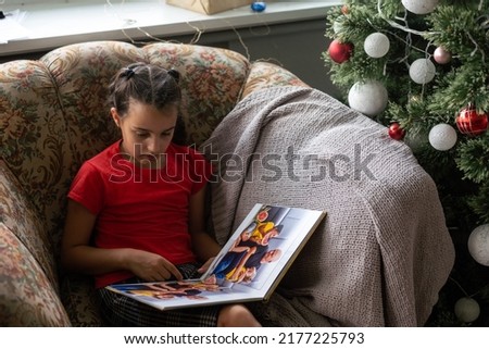 a little girl looking at a photo album in the living room