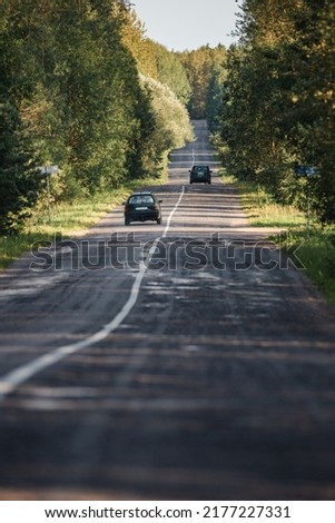 Travel by car. Asphalt road going into the distance through the forest with the sun breaking through the trees.