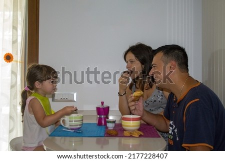 Image of a smiling family in the morning while having breakfast in the kitchen. The right charge of energy to face the day