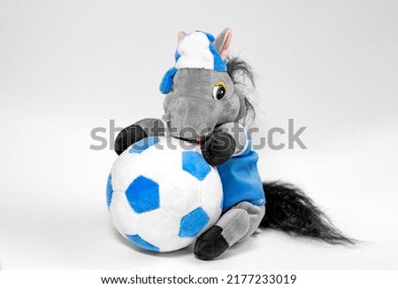 A donkey toy with a ball, isolated on a white background. A plush donkey is a soft toy for children. Close up