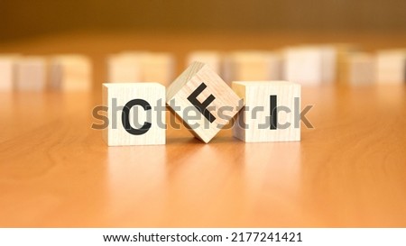 CFI text on wooden blocks, financial business concept, blue background. CFI - short for Company Financial Instructions