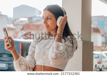latin girl with headphones and mobile phone or smartphone listening to music