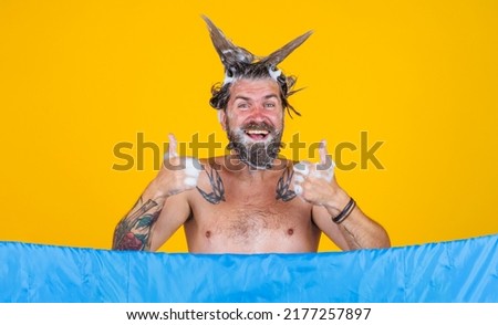 Bearded man taking shower shows thumbs up. Male with foam on head. Hair care. Bathing. Showering.
