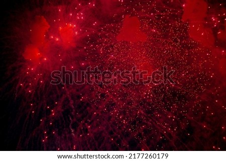 A bright firework with a red glowing center with red sparks and smoke flying towards the background of the night sky. High quality photo