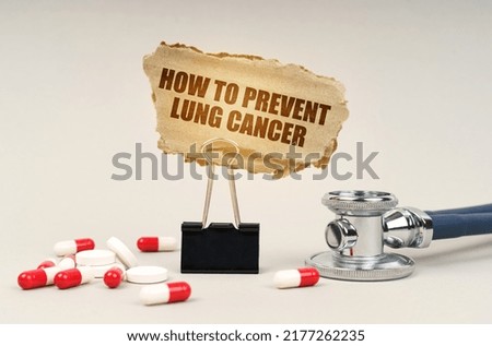 Medical concept. Near the stethoscope are pills and a clip with a cardboard sign - How to Prevent Lung Cancer