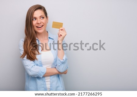 Credit card in hand of smiling woman with long hair looking away dressed blue white shirt isolated portrait  