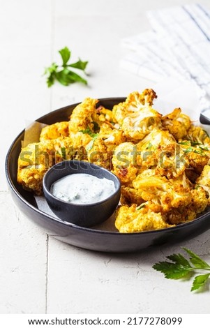 Baked spicy cauliflower wings with yogurt sauce in a black plate. Vegan diet recipe concept. Royalty-Free Stock Photo #2177278099