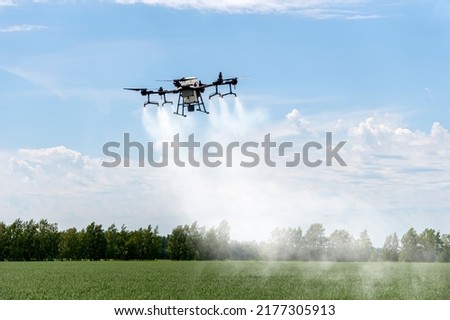 Modern technologies in agriculture. industrial drone flies over a green field and sprays useful pesticides to increase productivity and destroys harmful insects. increase productivity Royalty-Free Stock Photo #2177305913