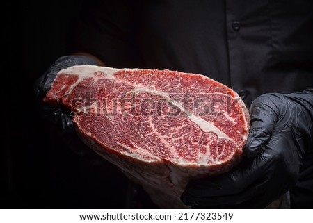 Chef prepares raw Japanese wagyu beef with dark background. Royalty-Free Stock Photo #2177323549