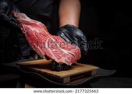 Chef prepares raw Japanese wagyu beef with dark background. Royalty-Free Stock Photo #2177325663