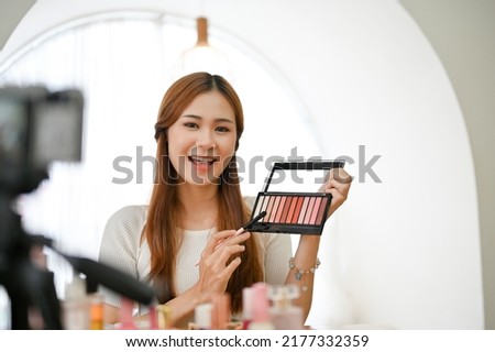 Talented young Asian female beauty blogger or influencer giving advice and reviews after using the eye shadows cosmetic product in live-streaming on social media. Royalty-Free Stock Photo #2177332359