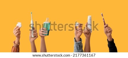 Many hands with toothbrushes, paste, mouth rinse and dental floss on yellow background Royalty-Free Stock Photo #2177361167