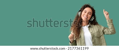 Young African-American woman listening to music and dancing on green background with space for text