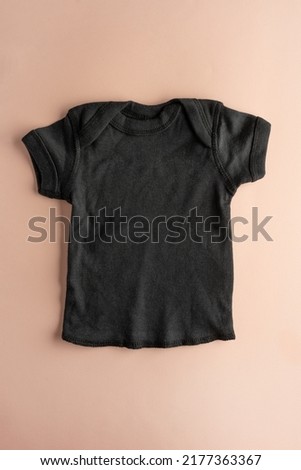 Black cotton children's t-shirt. Isolated on a pink background. Clothes for little girls. Flat layout for the design and placement of the logo, advertising. Close-up.