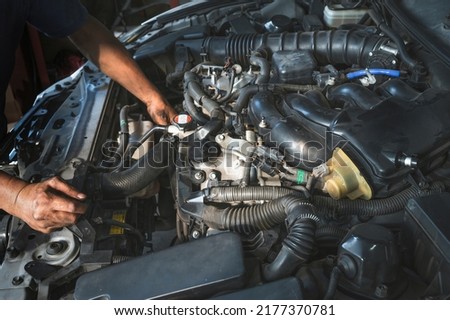 Auto mechanic checking a car radiator hose. Royalty-Free Stock Photo #2177370781