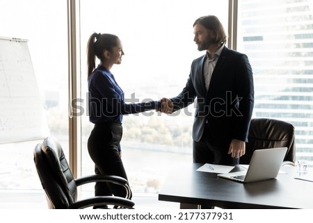 Young Caucasian businessman shake hand of happy female client or colleague close deal at office meeting. Happy business partners handshake get acquainted greeting at briefing. Cooperation concept. Royalty-Free Stock Photo #2177377931