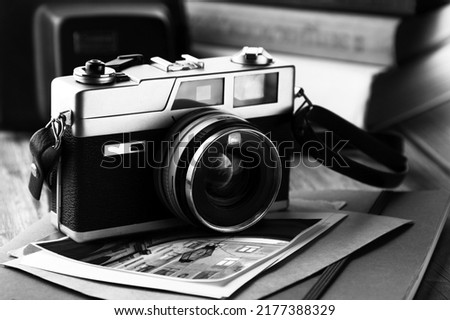 Retro photo camera on the background of old photos and books. Close-up. Selective focus