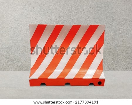 Red and white plastic blocks the walkway. on the cement background