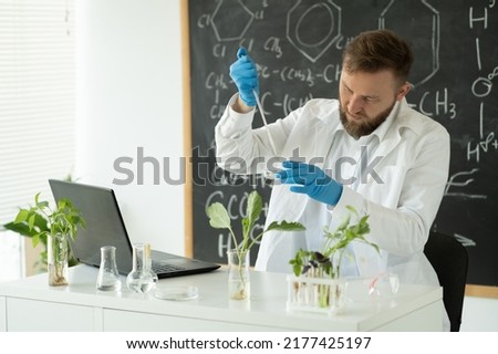 Biotechnologist is researching on laptop computer. Scientist working at microbiology laboratory. man is conducting experiments, tests with plants. Biologist workplace concept.